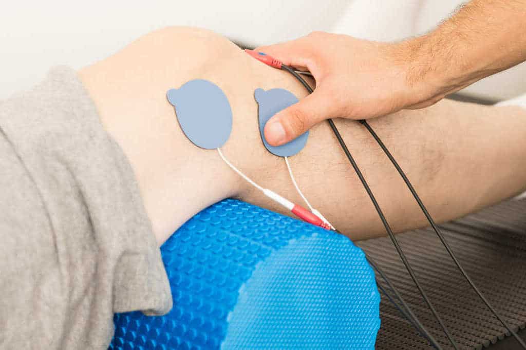 fisioterapeuta posicionamiento de mano electrodos rodilla paciente